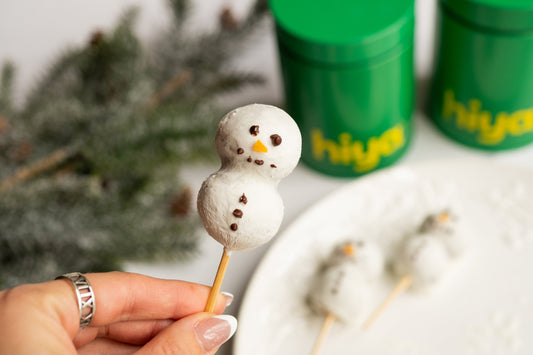 Snowman cake pops made from a chocolate-almond flour batter dipped in yogurt and decorated with dark chocolate eyes and a fruit nose.