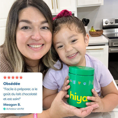 Mom and daughter smiling with green Hiya vitamin tablet container in kitchen, healthy kids nutrition
