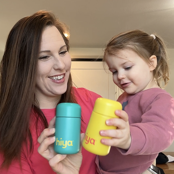 Mom and child holding colorful vitamin tablets in Hiya containers for kids' nutrition