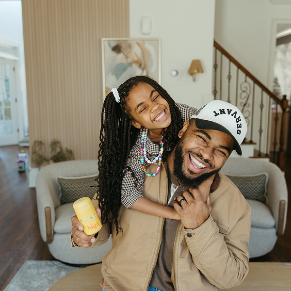 Father and daughter smiling with kids vitamin tablet bottle in cozy home setting