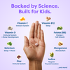 Hand holding kids' vitamin tablet with science-backed nutrients like Vitamin C, D, B12, Zinc for immune, sleep, growth